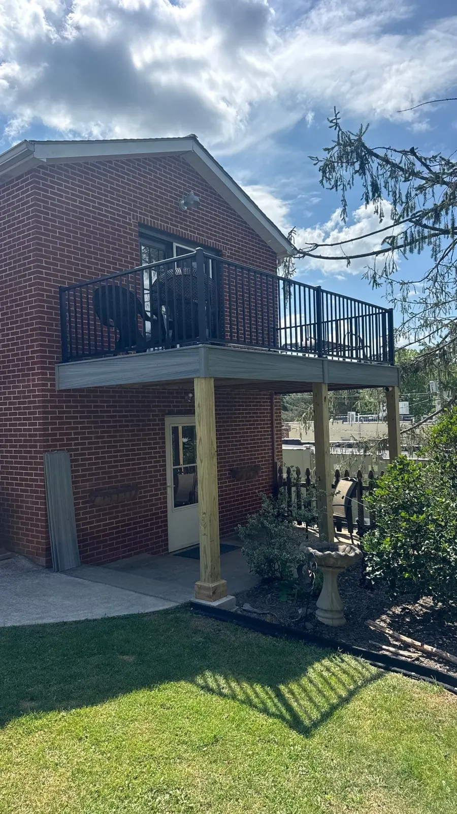 Elevated composite deck with black cable railing on a brick home
