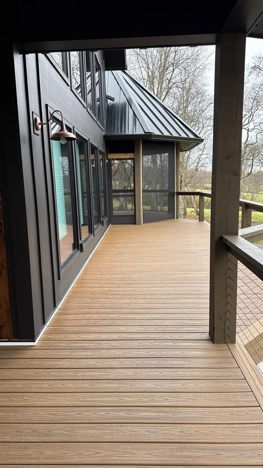 Golden-brown composite deck at a modern home with black-framed glass doors