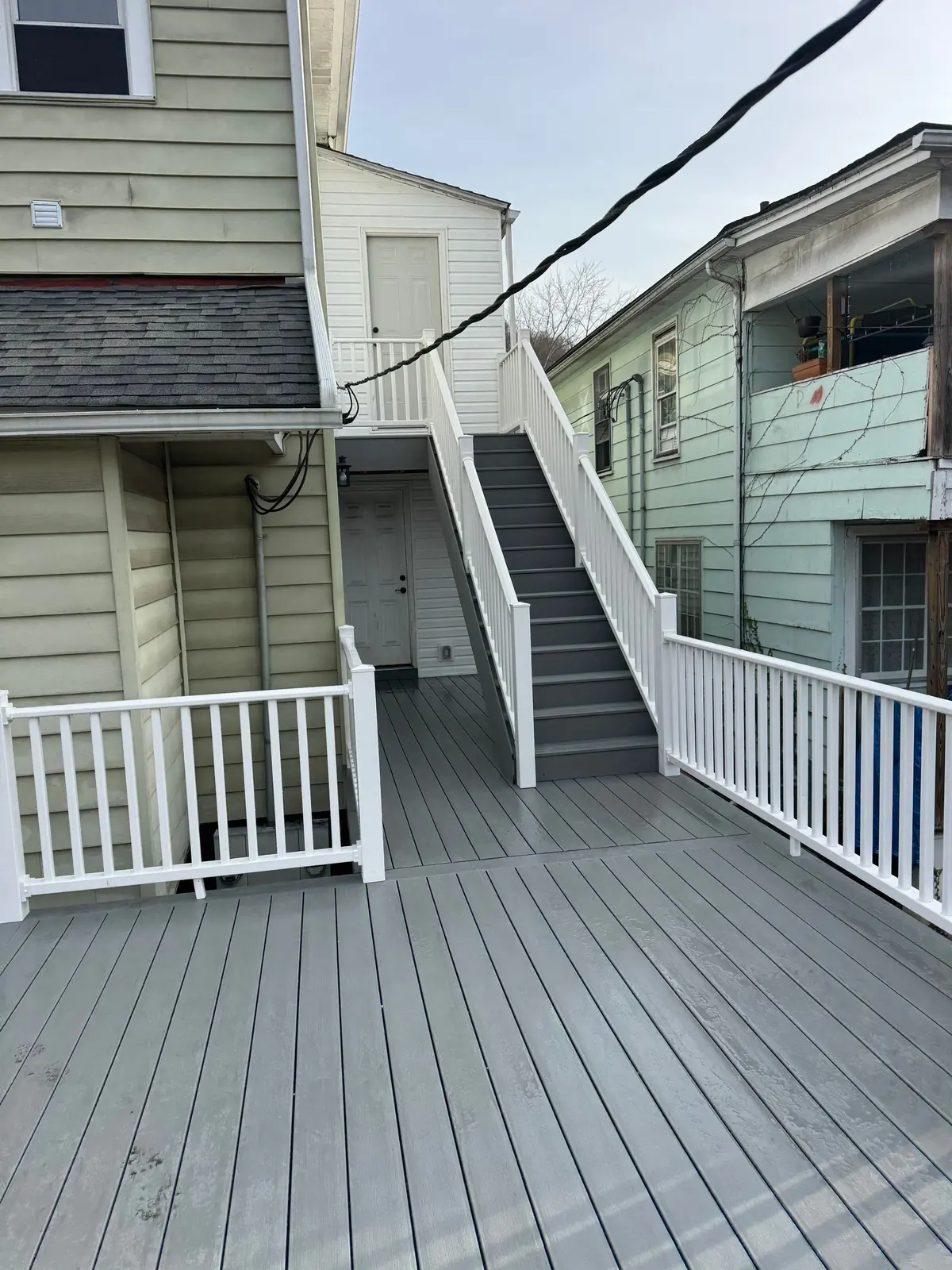 Gray composite deck with white vinyl railing and transition stairs
