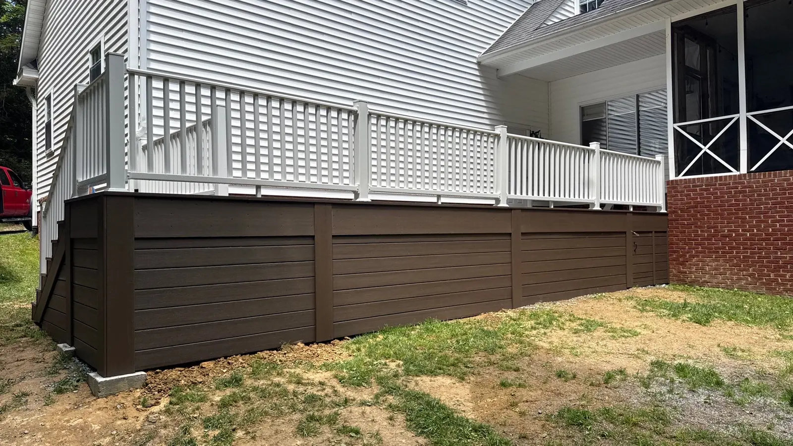Deck with white vinyl railing and lattice skirting in a landscaped backyard