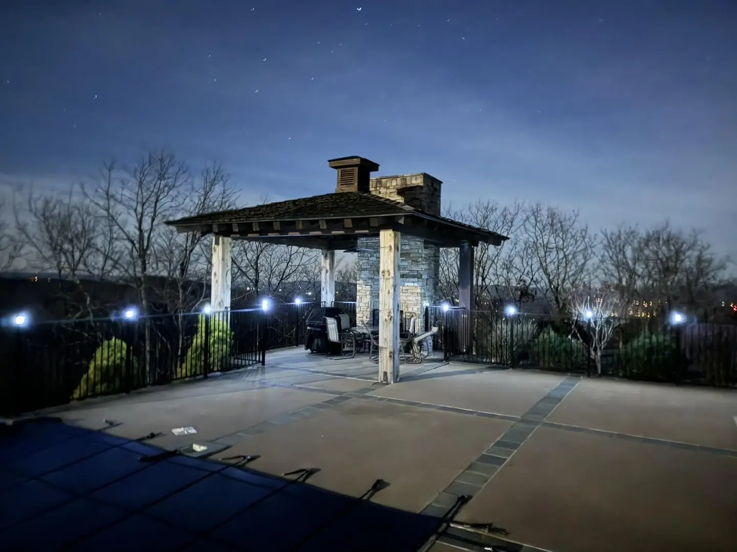 Outdoor pergola with stone fireplace at night