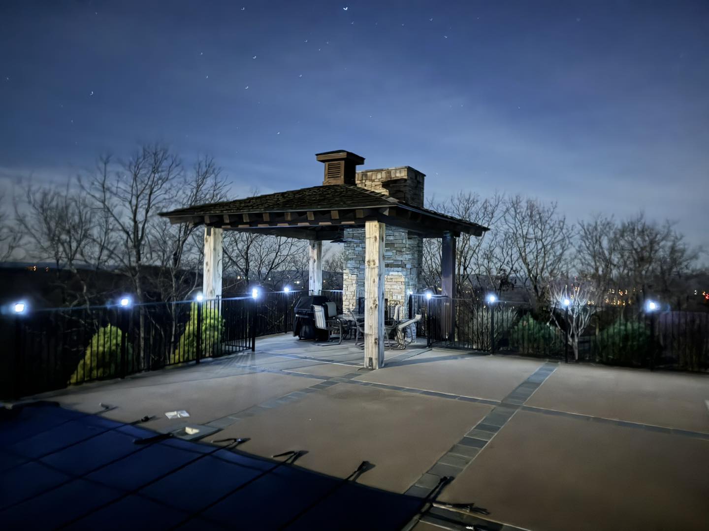 Outdoor pergola with stone fireplace at night