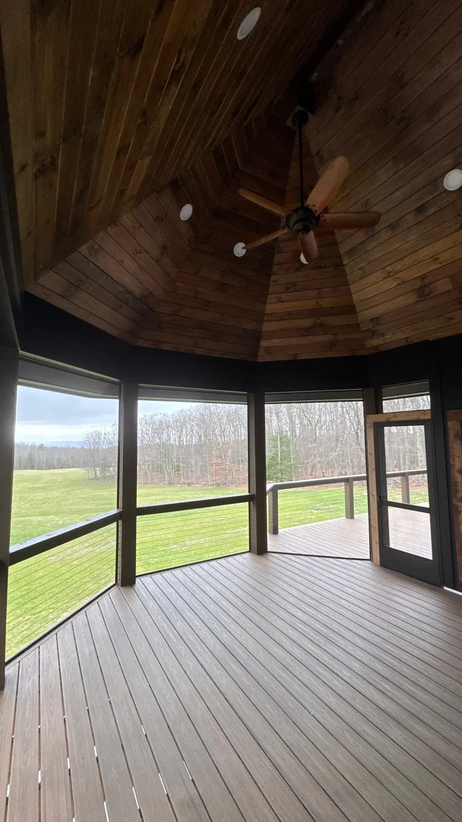 Screened porch interior with composite flooring and open-field view