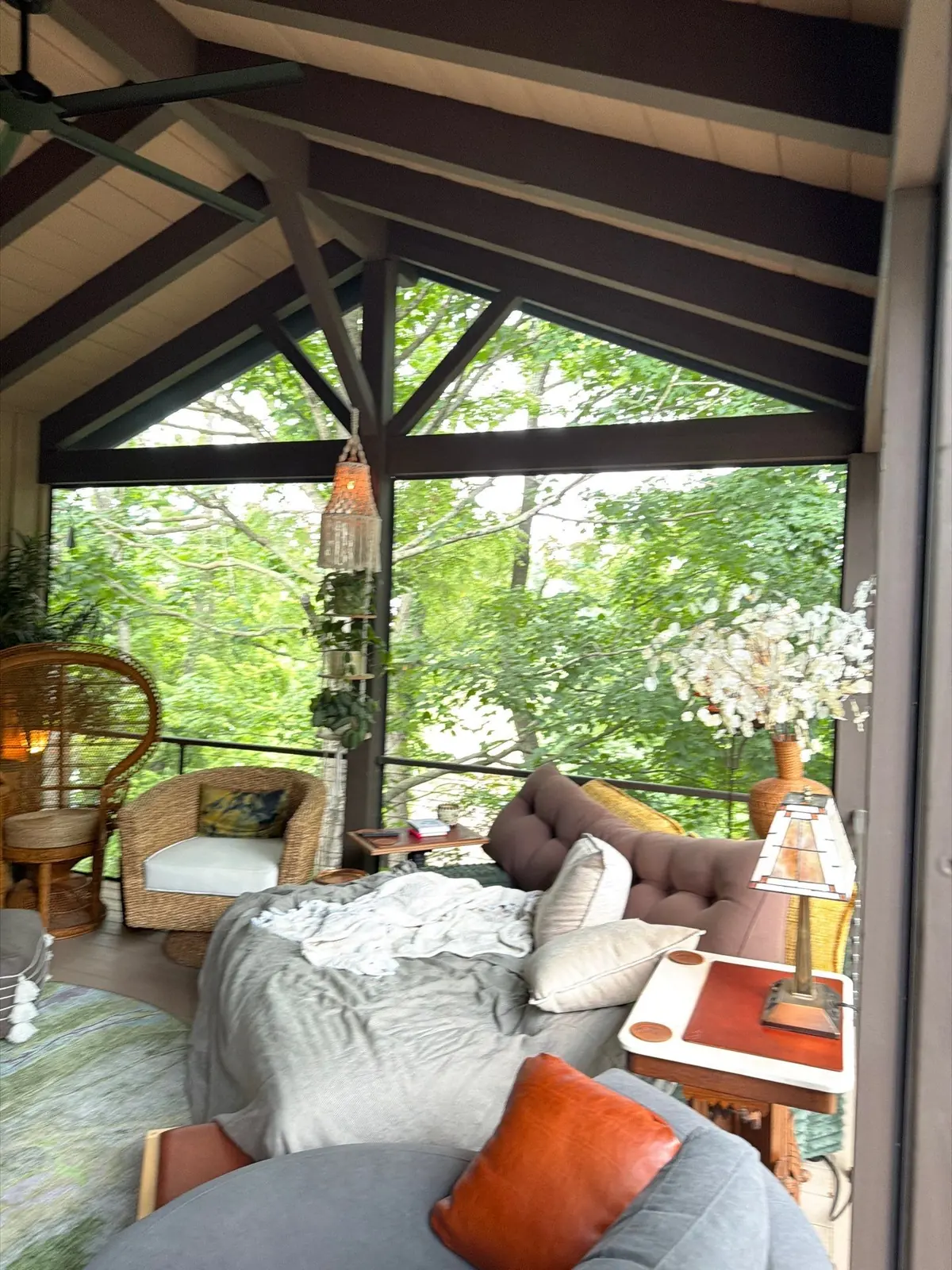 Inside a screened porch with dark beams and woodland views