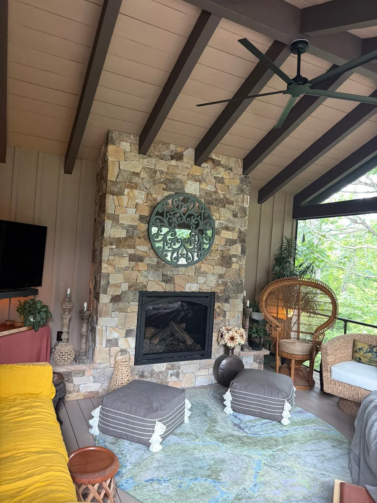 Screened porch living room with floor-to-ceiling stone fireplace and beamed ceiling