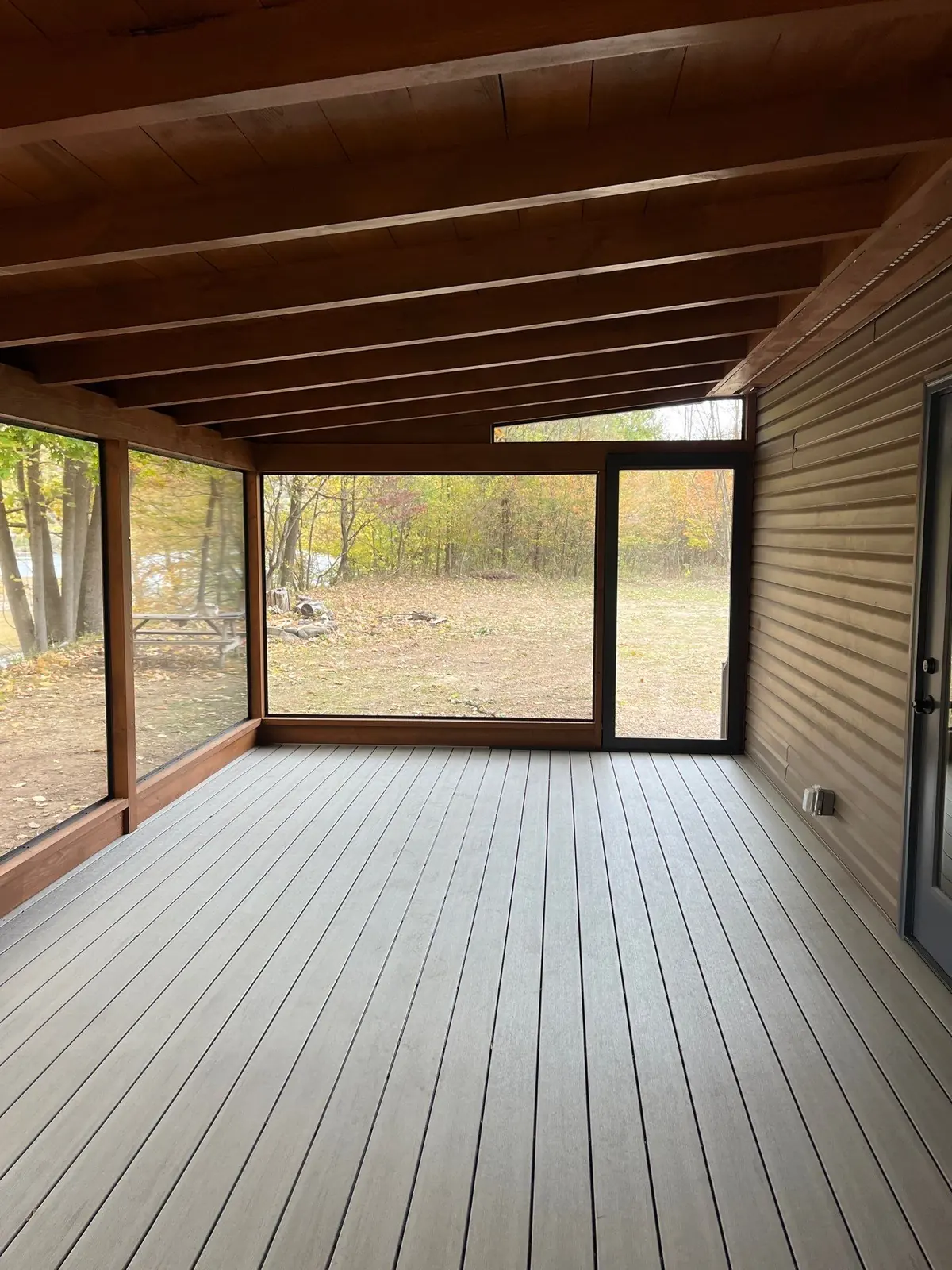 Screened porch with timber beams, large screen openings and forest view