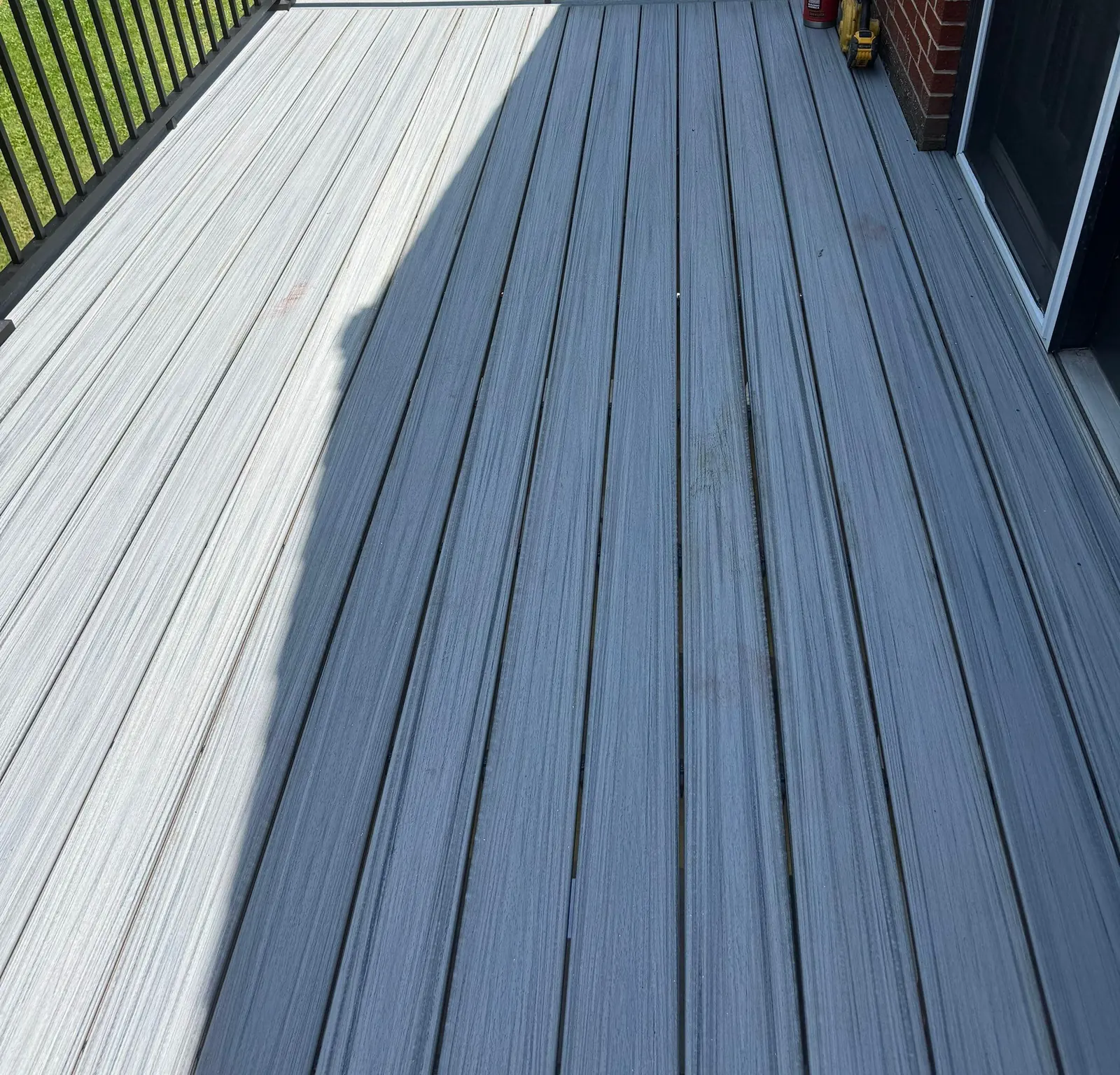 Two-tone composite decking with black aluminum railing on a brick home